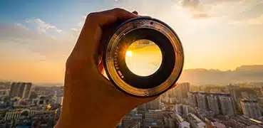 Hand holding a camera lens up to the horizon